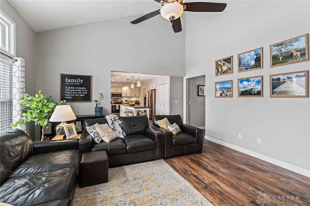 living room featuring ceiling fan, wood-type flooring, and a high ceiling