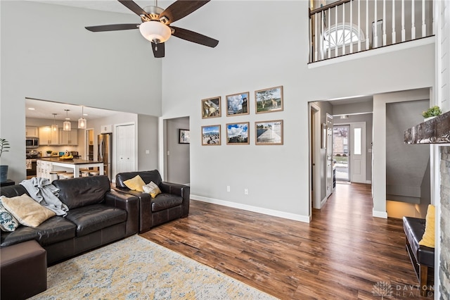 living room featuring ceiling fan, a towering ceiling, and dark hardwood / wood-style flooring