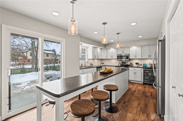 kitchen featuring decorative light fixtures, white cabinetry, sink, stainless steel appliances, and dark wood-type flooring