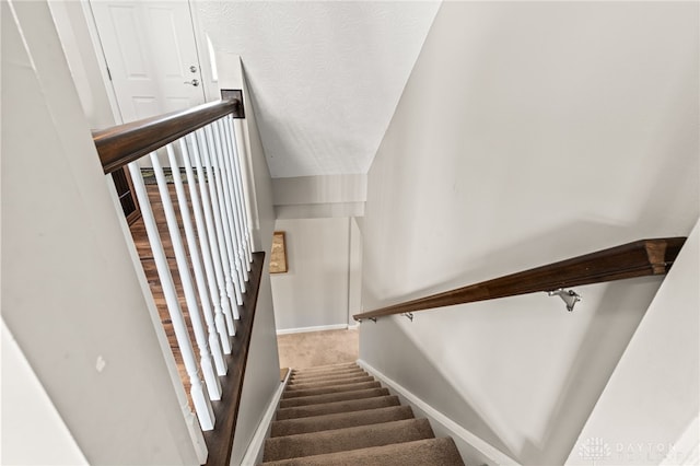 stairway featuring carpet floors and a textured ceiling