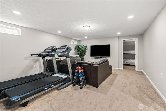 exercise area featuring light carpet and a textured ceiling