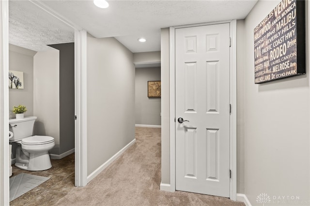 hall featuring light carpet and a textured ceiling