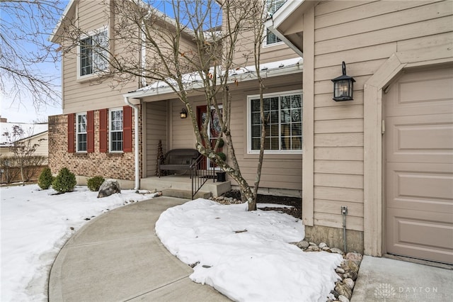 snow covered property entrance with a garage