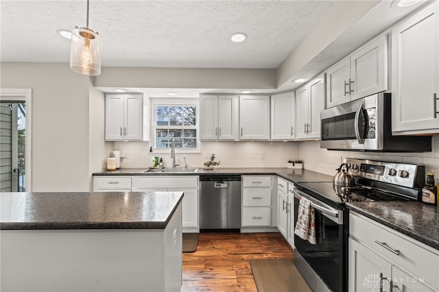 kitchen with white cabinetry, stainless steel appliances, sink, and pendant lighting