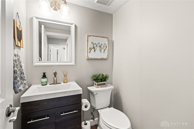 bathroom featuring vanity, a textured ceiling, and toilet