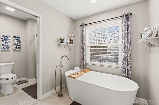 bathroom featuring a bath, tile patterned floors, and toilet