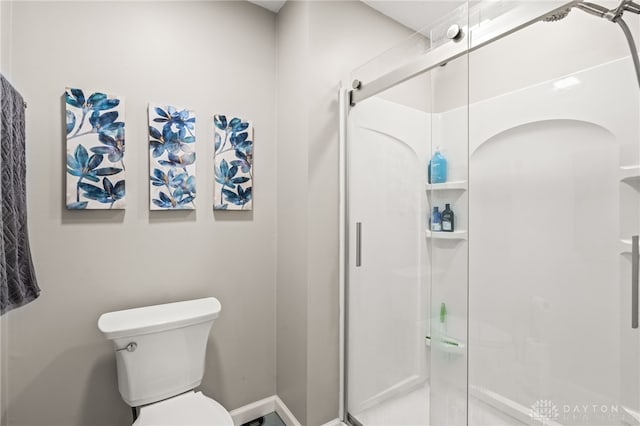 bathroom featuring a shower with shower door and toilet