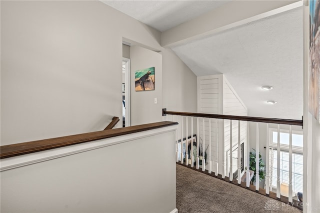 hall featuring lofted ceiling, a textured ceiling, and carpet flooring