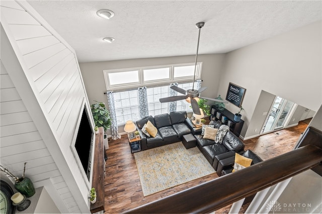 living room with ceiling fan, dark hardwood / wood-style floors, high vaulted ceiling, and a textured ceiling