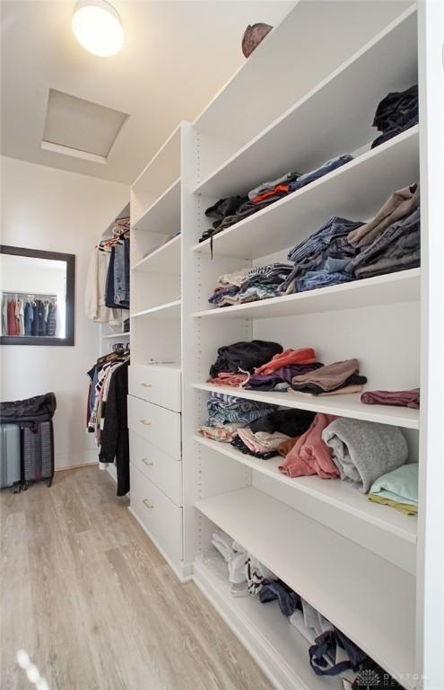 walk in closet with light hardwood / wood-style floors