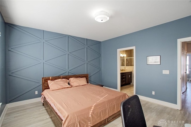 bedroom featuring connected bathroom and light wood-type flooring