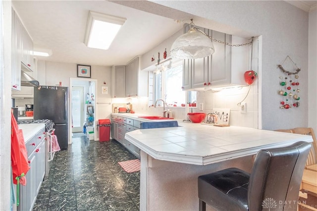 111 W Pinehurst St, Sidney, OH 45365 - kitchen featuring a sink, freestanding refrigerator, a kitchen bar, a peninsula, and backsplash