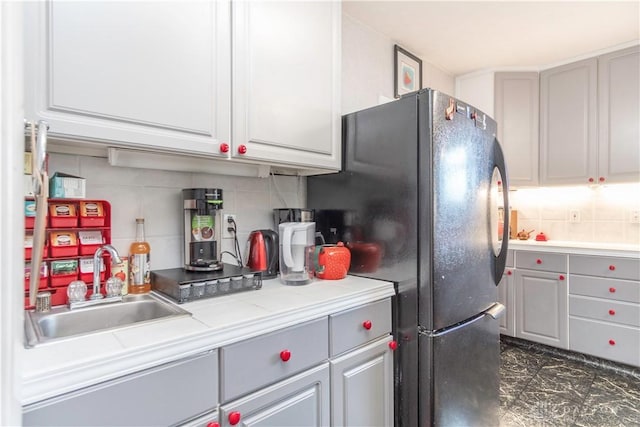 111 W Pinehurst St, Sidney, OH 45365 - kitchen featuring tasteful backsplash, gray cabinets, freestanding refrigerator, light countertops, and a sink