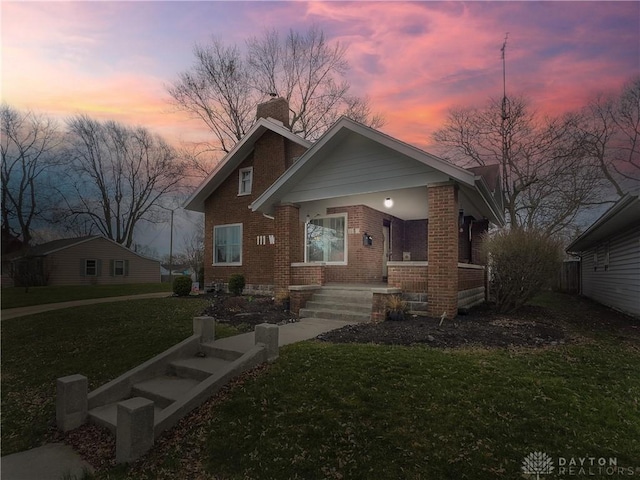 111 W Pinehurst St, Sidney, OH 45365 - bungalow-style home featuring covered porch, brick siding, a chimney, and a front yard