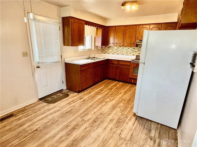 kitchen featuring tasteful backsplash, sink, white fridge, range, and light hardwood / wood-style flooring