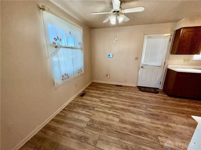 unfurnished dining area with ceiling fan and light hardwood / wood-style flooring