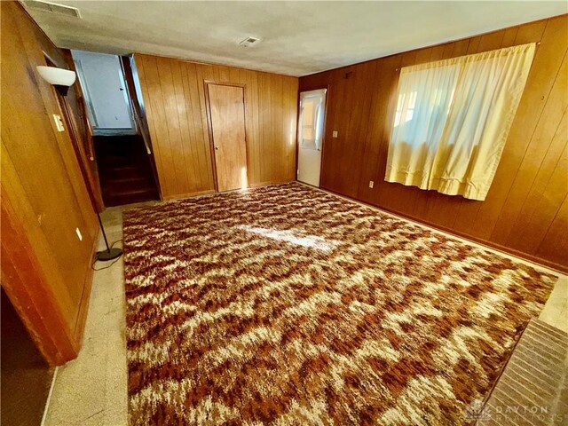 unfurnished bedroom featuring carpet floors and wood walls