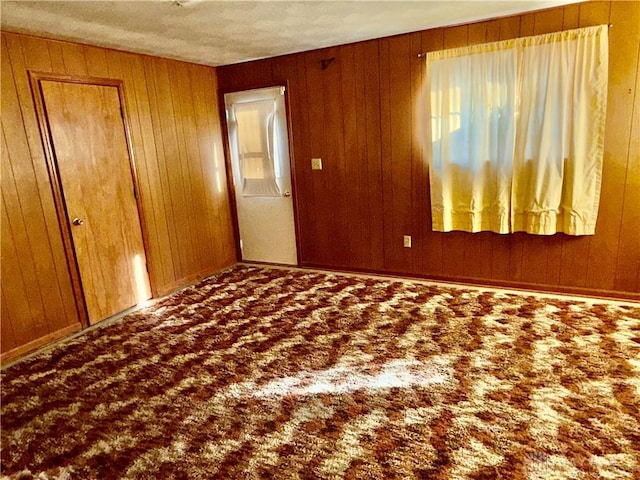 unfurnished room with wood walls and carpet