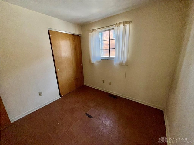 unfurnished bedroom with parquet flooring and a closet