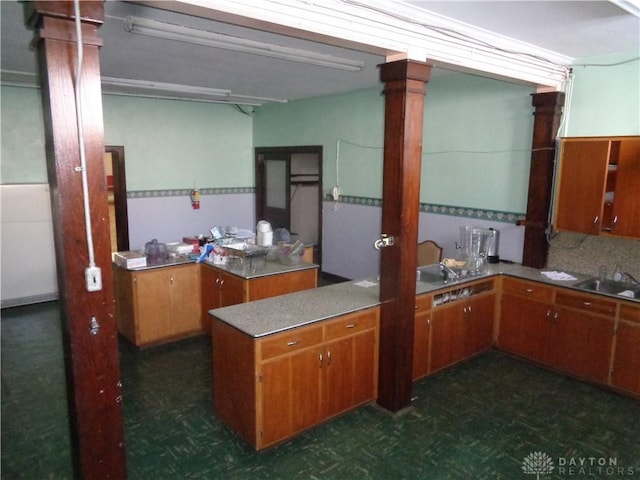 kitchen with sink, dark parquet floors, kitchen peninsula, and ornate columns