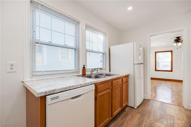 kitchen featuring ceiling fan, white appliances, sink, and light wood-type flooring