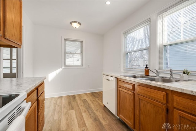 kitchen with a healthy amount of sunlight, sink, white appliances, and light hardwood / wood-style floors