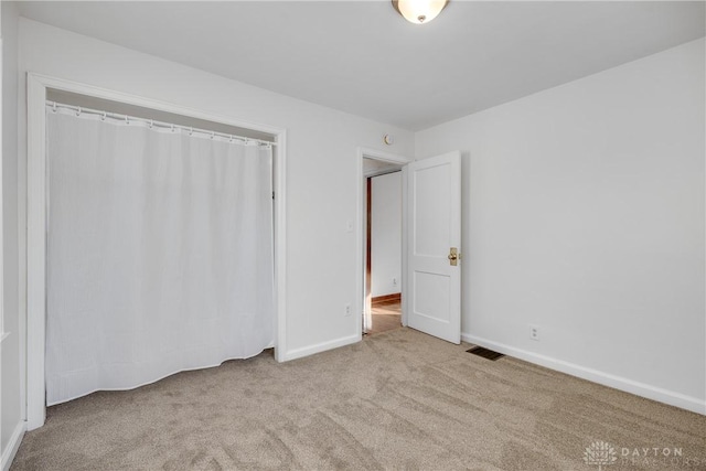 unfurnished bedroom with light carpet and a closet