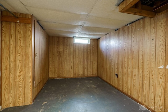 basement with a paneled ceiling and wooden walls