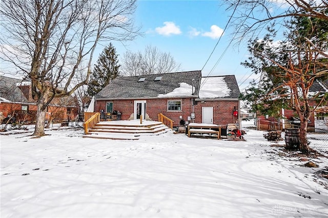 snow covered back of property featuring a deck