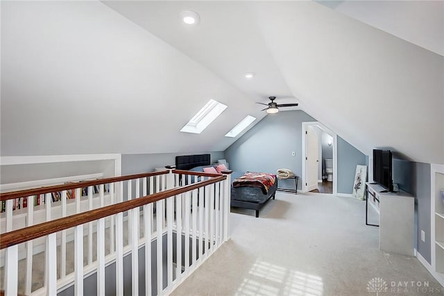 additional living space with vaulted ceiling with skylight, light colored carpet, and ceiling fan