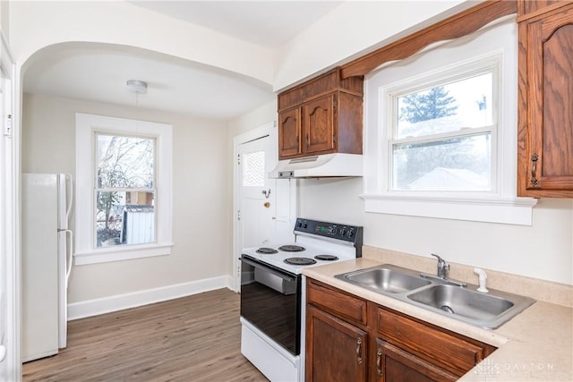 kitchen featuring sink, electric range oven, white fridge, pendant lighting, and hardwood / wood-style floors