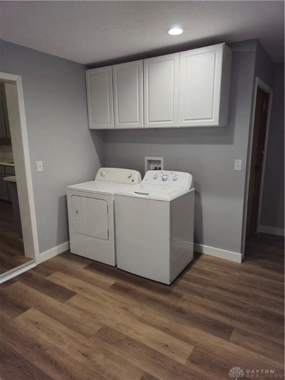 clothes washing area featuring dark wood-type flooring, cabinets, and washing machine and clothes dryer