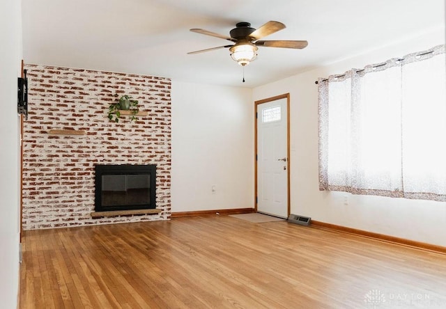 unfurnished living room featuring ceiling fan, wood-type flooring, and a fireplace