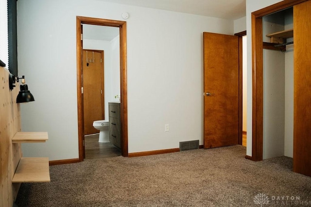 unfurnished bedroom with ensuite bath, a closet, and carpet flooring