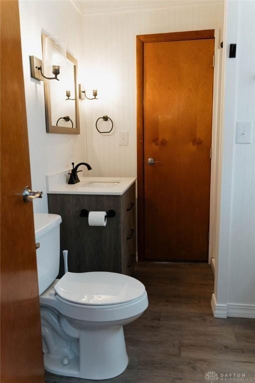 bathroom with vanity, wood-type flooring, crown molding, and toilet