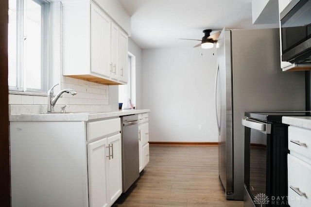 kitchen with tasteful backsplash, light hardwood / wood-style flooring, appliances with stainless steel finishes, ceiling fan, and white cabinets