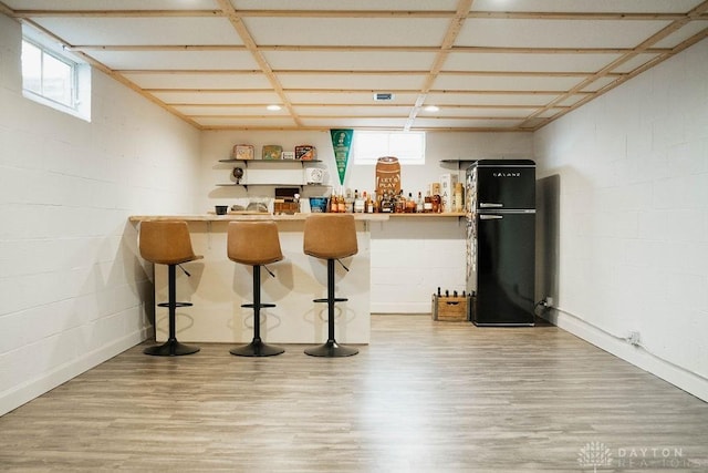 bar featuring black fridge and hardwood / wood-style floors