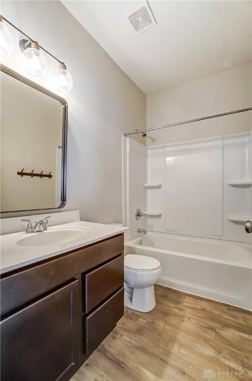 full bathroom featuring wood-type flooring, vanity, shower / bathtub combination, and toilet