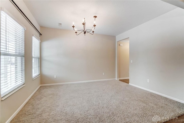 empty room featuring carpet floors and a notable chandelier