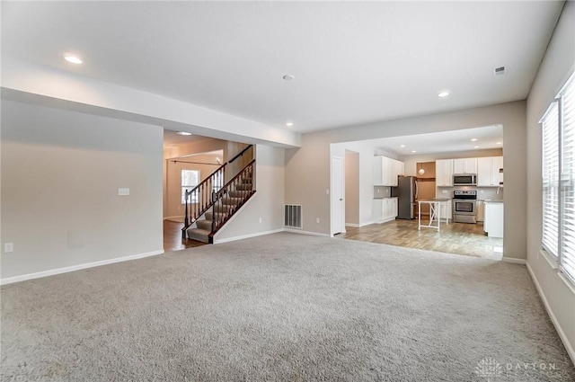 unfurnished living room featuring a wealth of natural light and light carpet