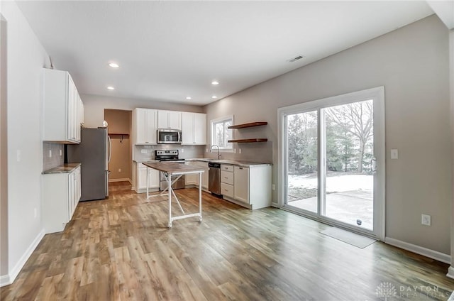 kitchen featuring sink, light hardwood / wood-style flooring, white cabinetry, stainless steel appliances, and tasteful backsplash