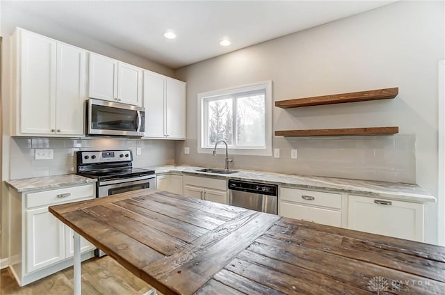 kitchen featuring appliances with stainless steel finishes, butcher block countertops, sink, white cabinets, and decorative backsplash