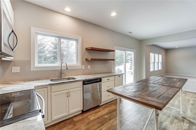 kitchen with appliances with stainless steel finishes, tasteful backsplash, white cabinetry, wood-type flooring, and sink