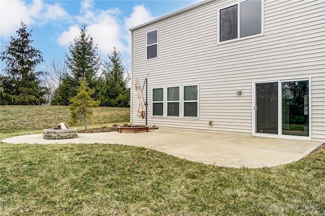 rear view of property featuring a lawn, a patio area, and a fire pit