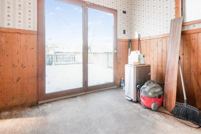 doorway with concrete floors and wood walls