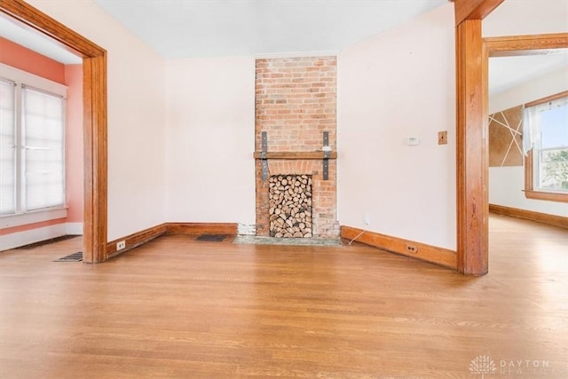 unfurnished living room featuring a brick fireplace and light hardwood / wood-style floors