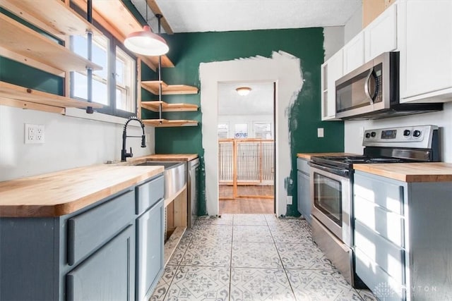 kitchen with gray cabinetry, wood counters, appliances with stainless steel finishes, and white cabinets