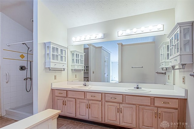 bathroom featuring a tile shower, vanity, and a textured ceiling