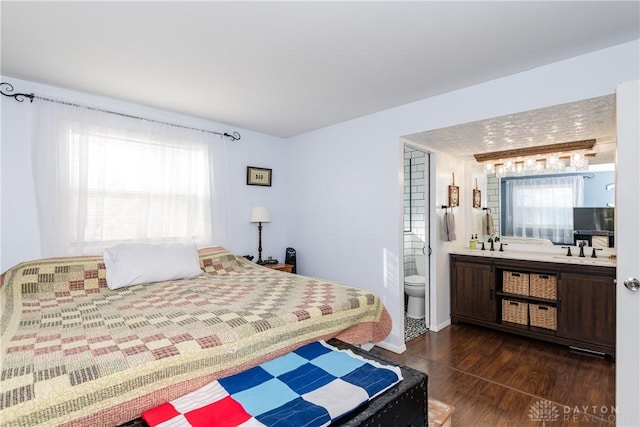 bedroom featuring dark hardwood / wood-style flooring, sink, and ensuite bathroom