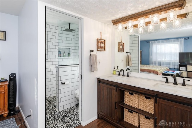 bathroom featuring toilet, a textured ceiling, a tile shower, vanity, and hardwood / wood-style flooring